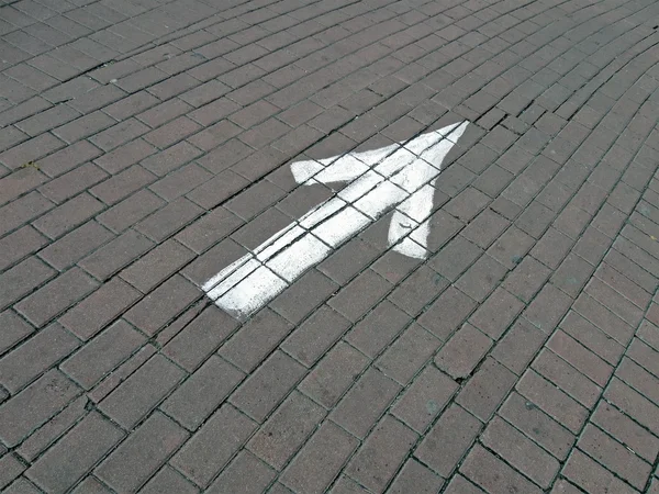Dipinto bianco direzione segno su strada di mattoni, trasporto . — Foto Stock