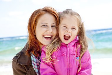 Two sisters 4 and 21 years old at the beach in sunny autumn day. clipart