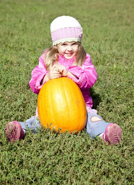 Little gardener girl with pumpkin at green grass — Stock Photo, Image