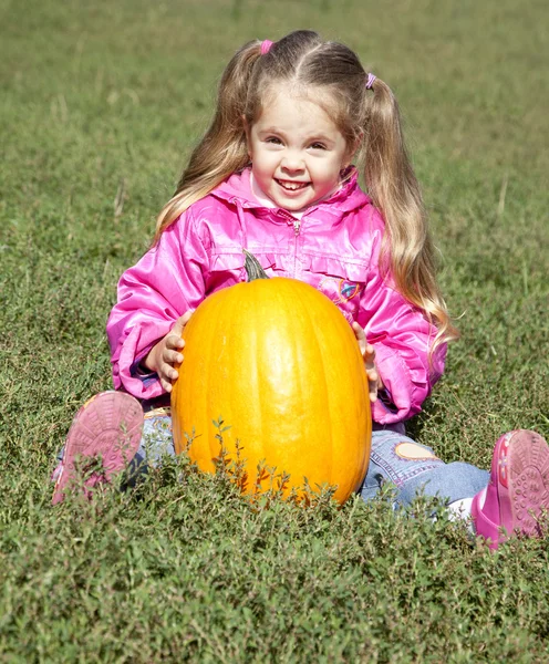 Little gardener girl with pumpkin at green grass — Stock Photo, Image