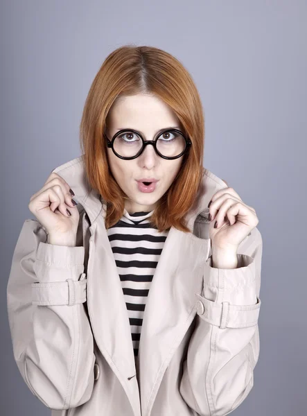 Rusovlasá dívka v brýle a plášť. — Stock fotografie