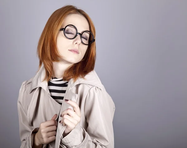 Rusovlasá dívka v brýle a plášť. — Stock fotografie