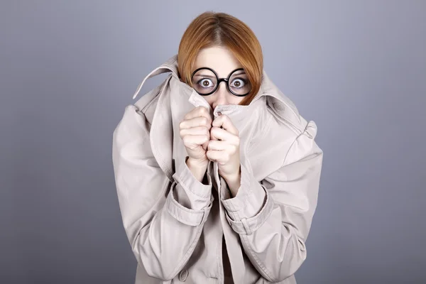 Escondiendo chica pelirroja en gafas y capa . — Foto de Stock