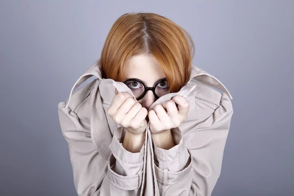 Escondendo menina de cabelos vermelhos em óculos e capa . — Fotografia de Stock