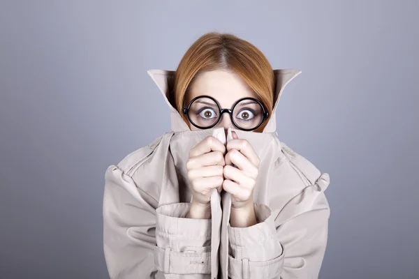 Escondiendo chica pelirroja en gafas y capa . —  Fotos de Stock