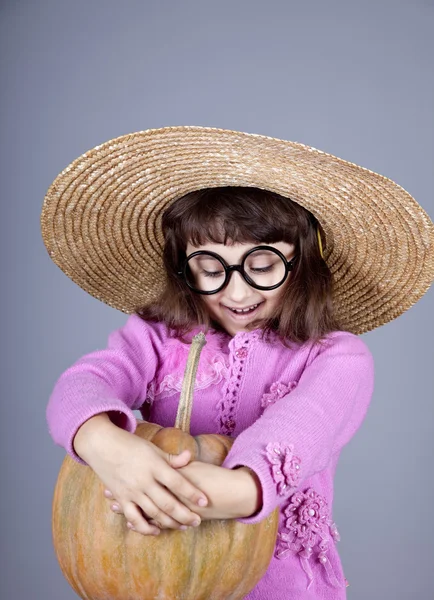 Funny girl v čepici a brýle, udržet dýně. — Stock fotografie