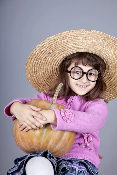 Funny girl in cap and glasses keeping pumpkin. — Stock Photo, Image