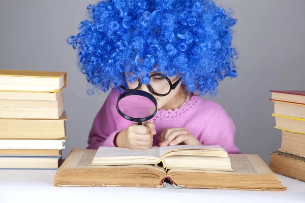 Grappig blauw-haired meisje met Vergrootglas en boeken. — Stockfoto