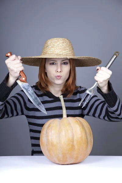 Funny girl in cap and fork with knife try to eat a pumpkin. — Stock Photo, Image