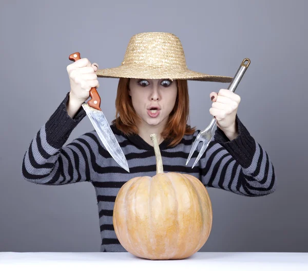Ragazza divertente in berretto e forchetta con coltello tenta di mangiare una zucca . — Foto Stock