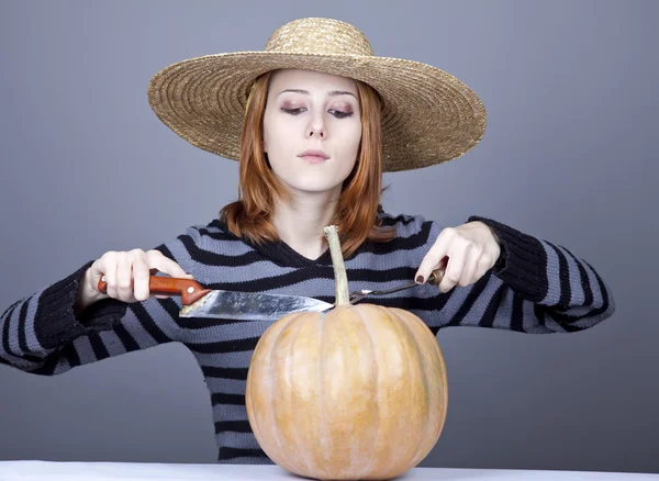 Grappig meisje in cap en vork met mes proberen te eten een pompoen. — Stockfoto
