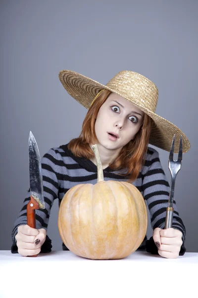 Ragazza divertente in berretto e forchetta con coltello tenta di mangiare una zucca . — Foto Stock