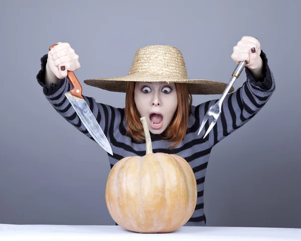 Забавная девушка в кепке и вилке с ножом пытается съесть тыкву . — стоковое фото
