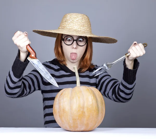 Chica divertida en gorra y tenedor con cuchillo tratar de comer una calabaza . —  Fotos de Stock