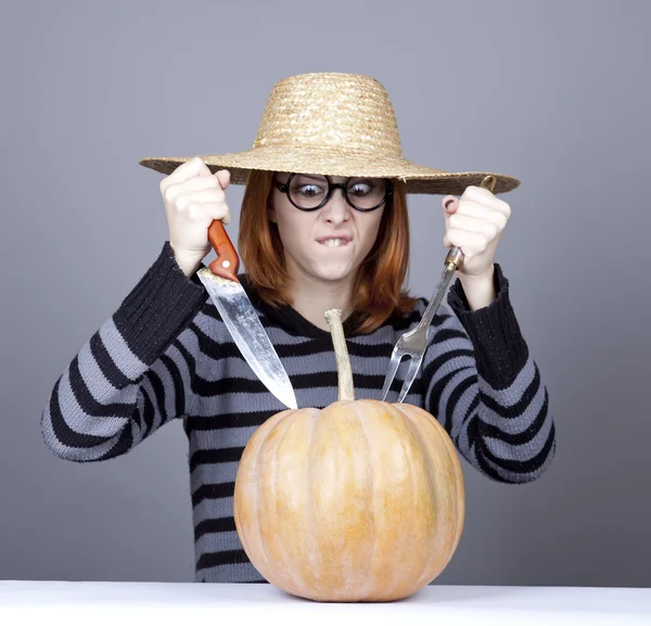 Chica divertida en gorra y tenedor con cuchillo tratar de comer una calabaza . —  Fotos de Stock