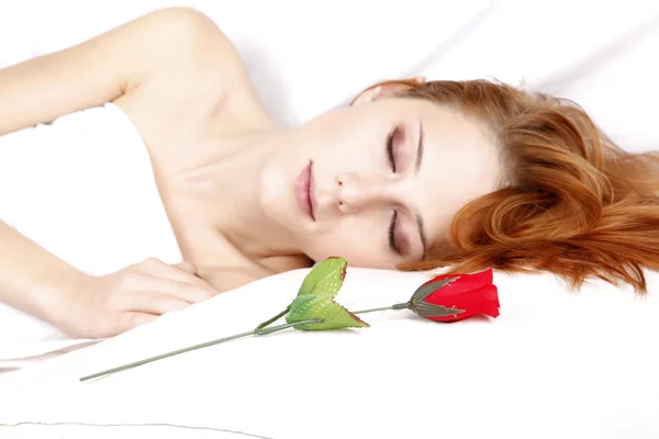 Uyuyan güzel kızıl saçlı kadının yanına kırmızı gül — Stok fotoğraf