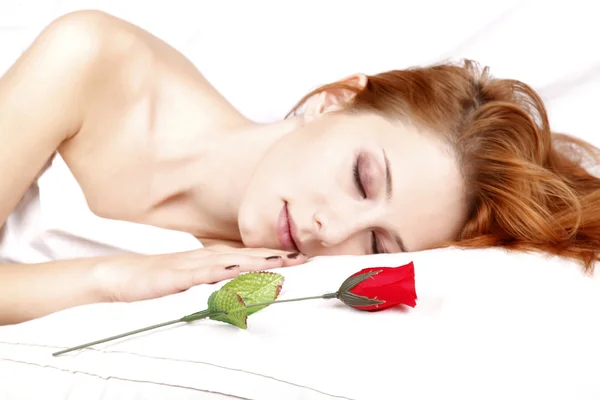 Rote Rose in der Nähe der hübschen rothaarigen schlafenden Frau — Stockfoto