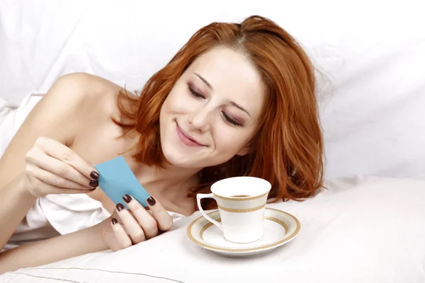 Kvinnan i vit liggande i sängen nära kopp kaffe. — Stockfoto