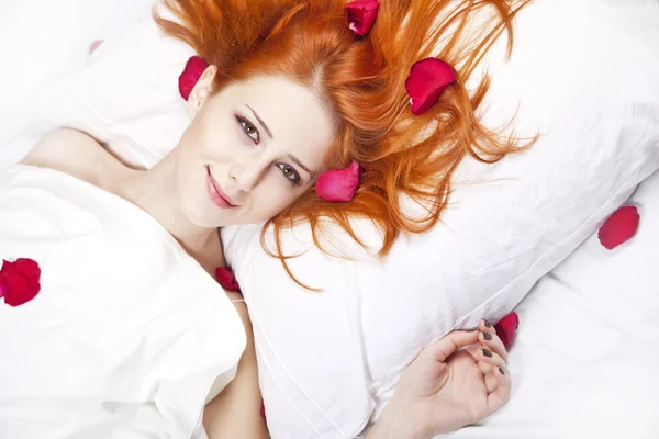 Menina ruiva bonita na cama com pétala de rosa . — Fotografia de Stock