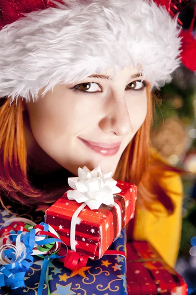 Funny girl in christmas cap with gift boxes — Stock Photo, Image
