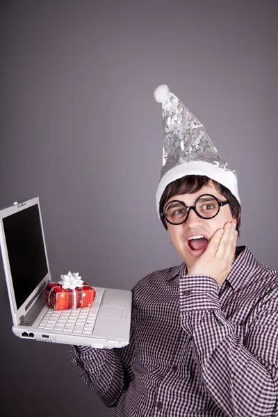 Hommes drôles dans la casquette de Noël avec boîte cadeau et ordinateur portable . — Photo