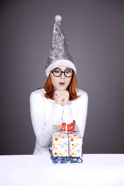 Chica en gorra de Navidad y vasos con cajas de regalo . — Foto de Stock