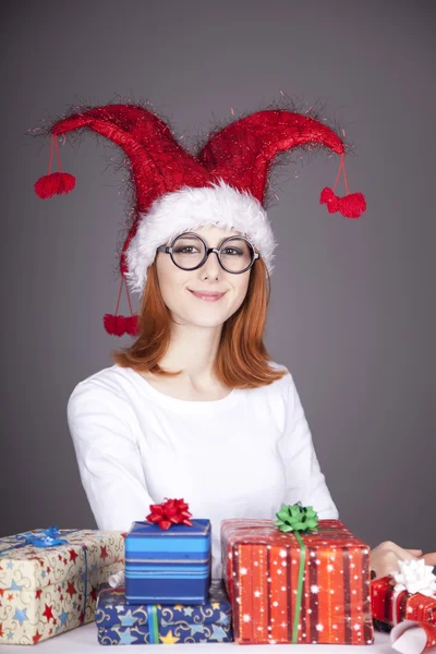 Дівчина в різдвяній шапці і окулярах з подарунковими коробками . — стокове фото