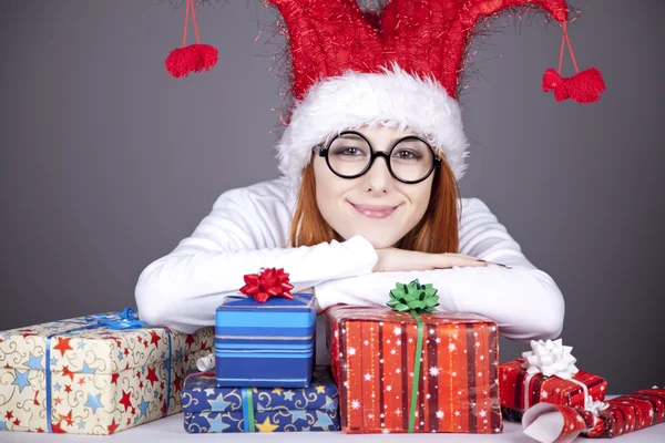 Fille dans la casquette de Noël et des lunettes avec des boîtes-cadeaux . — Photo