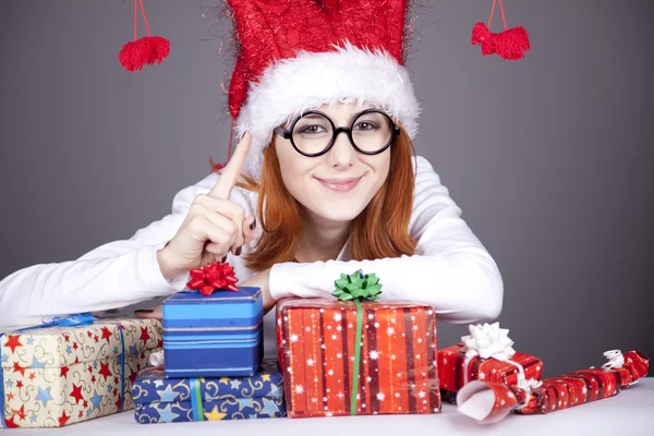 Girl in christmas cap and glasses with gift boxes. — Stock Photo, Image