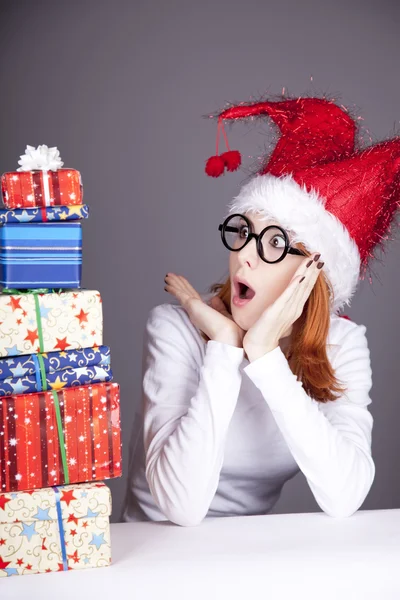 Girl in christmas cap and glasses with gift boxes. — Stock Photo, Image