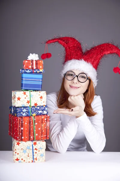 Chica en gorra de Navidad y vasos con cajas de regalo . — Foto de Stock