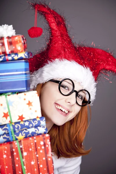 Vicces vörös hajú lány karácsonyi sapka, díszdobozok. — Stock Fotó