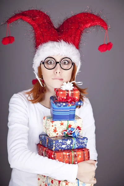 Fille dans la casquette de Noël et des lunettes avec des boîtes-cadeaux . — Photo