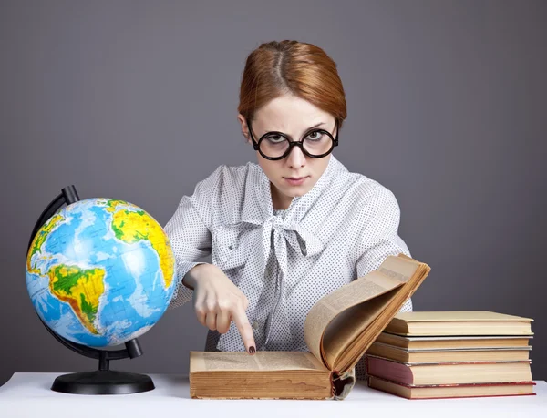 The young teacher in glasses with books and globe. — Stock Photo, Image