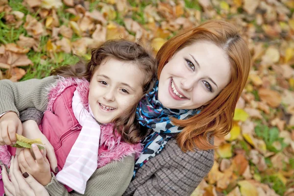 Two sisters sitting on the leafs in the park. — Stock Photo, Image