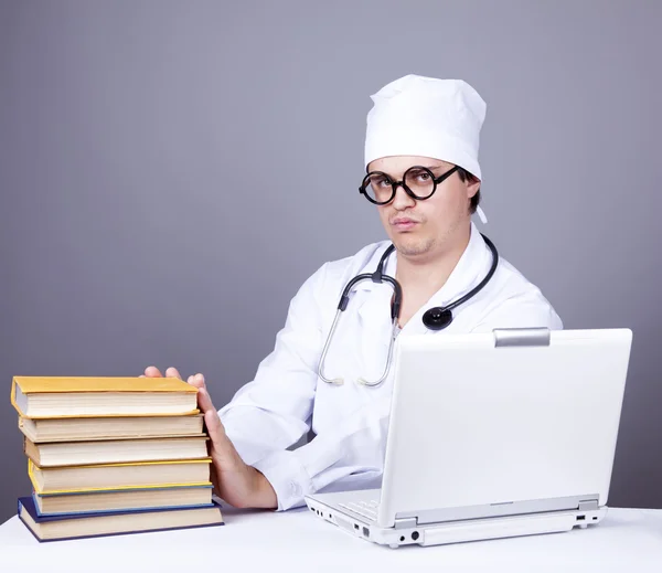 Молодий лікар з книгами та комп'ютером . — стокове фото