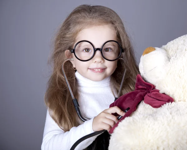Kleines Mädchen mit Stethoskop und Bärenjungtier. — Stockfoto