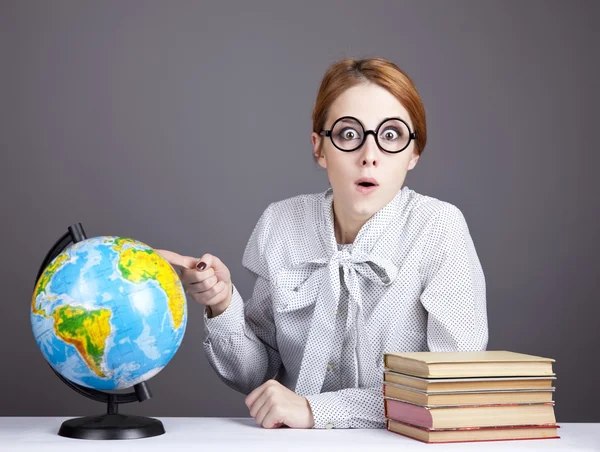 The young teacher in glasses with books and globe. Stock Photo