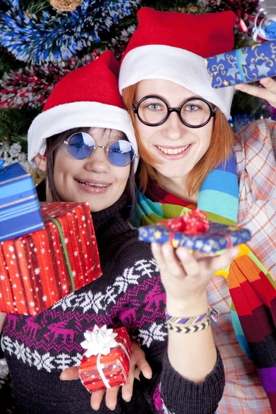 Two beautiful girls with gifts in christmas hats near christmas — Stock Photo, Image