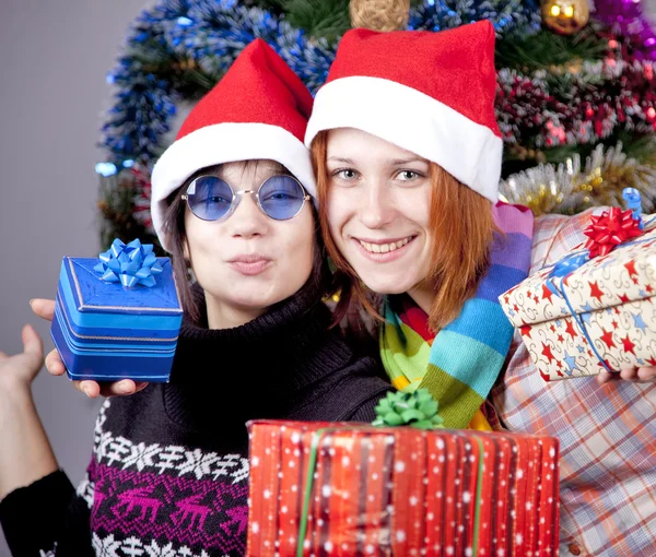 Δύο όμορφα κορίτσια με δώρα σε καπέλα Χριστουγέννων πριν από τα Χριστούγεννα — Φωτογραφία Αρχείου