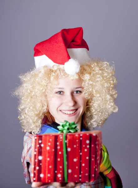 Girl in blonde wig and christmas hat show gift.