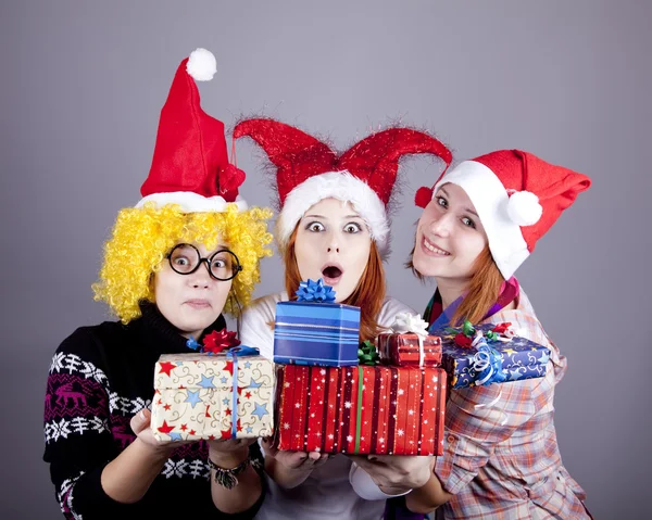 Drie vriendinnen in grappige hoeden met giften van Kerstmis. — Stockfoto