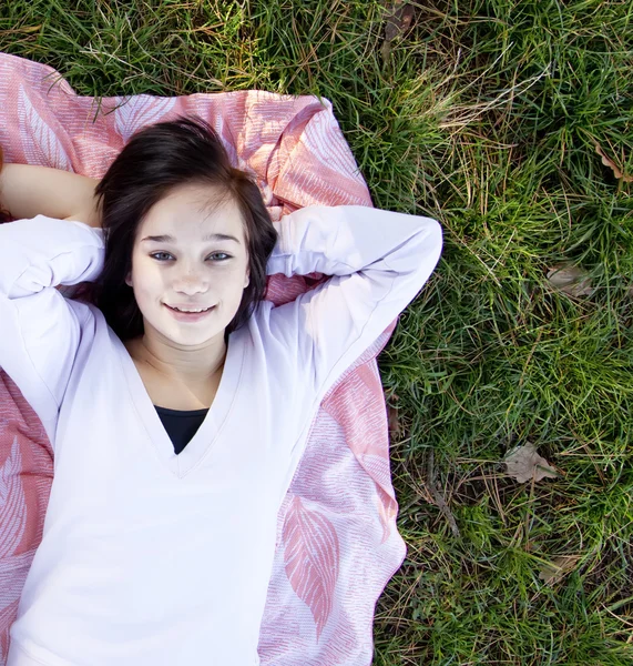 若い十代の少女は草でうそをつく. — ストック写真