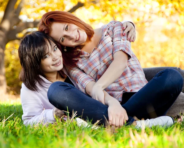Twee mooie tiener meisje op groen gras in het park. — Stockfoto