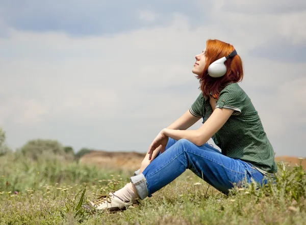 Chica de la moda joven con auriculares en la hierba en primavera . —  Fotos de Stock