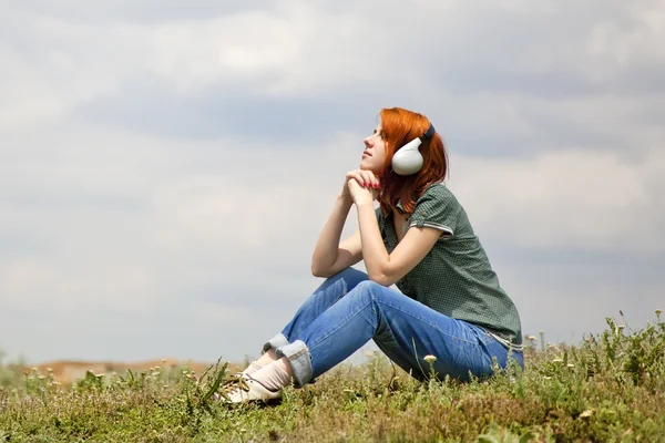 Mladá móda dívka s sluchátka na trávě v jarním období. — Stock fotografie
