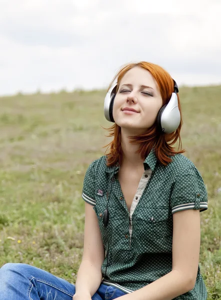 Chica de la moda joven con auriculares en la hierba en primavera . — Foto de Stock
