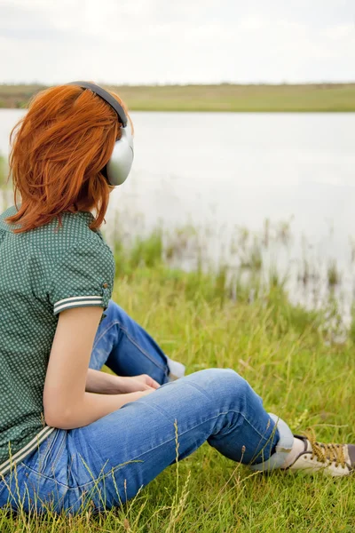 Young fashion girl with headphones at grass in spring time. — Stock Photo, Image