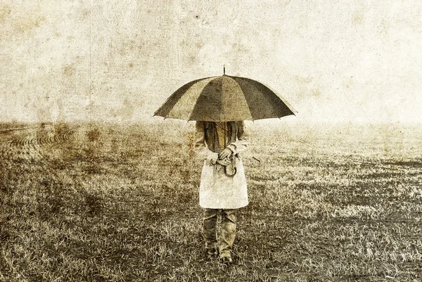 Girl with umbrella staying on field. — Stock Photo, Image