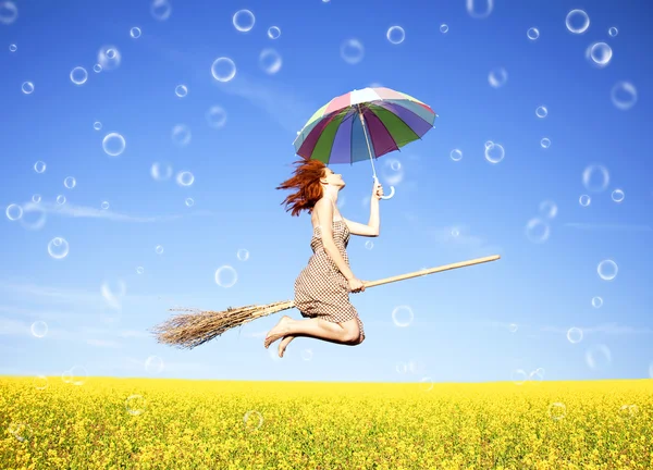 stock image Red-haired girl fly with umbrella over rape field and bubbles ar